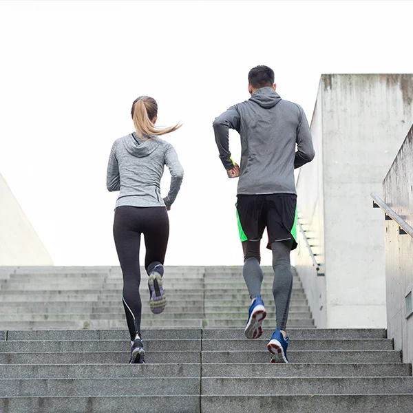 Two people in athletic wear run up a set of outdoor stairs, viewed from behind.