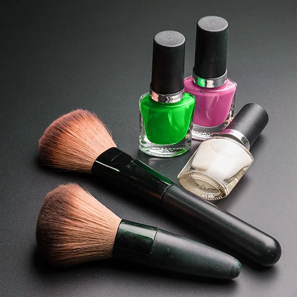 Make up brushes and nail polish on a dark tabletop