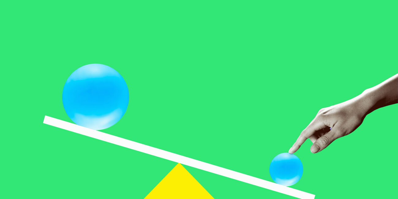 Hand holding down a see-saw with blue spheres