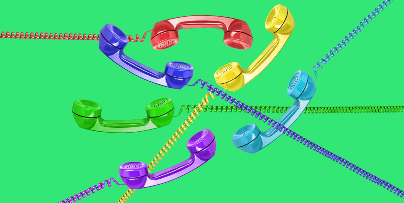 6 vintage landline telephone receivers of various color on green background