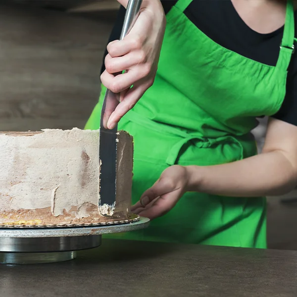 A woman is frosting a cake.