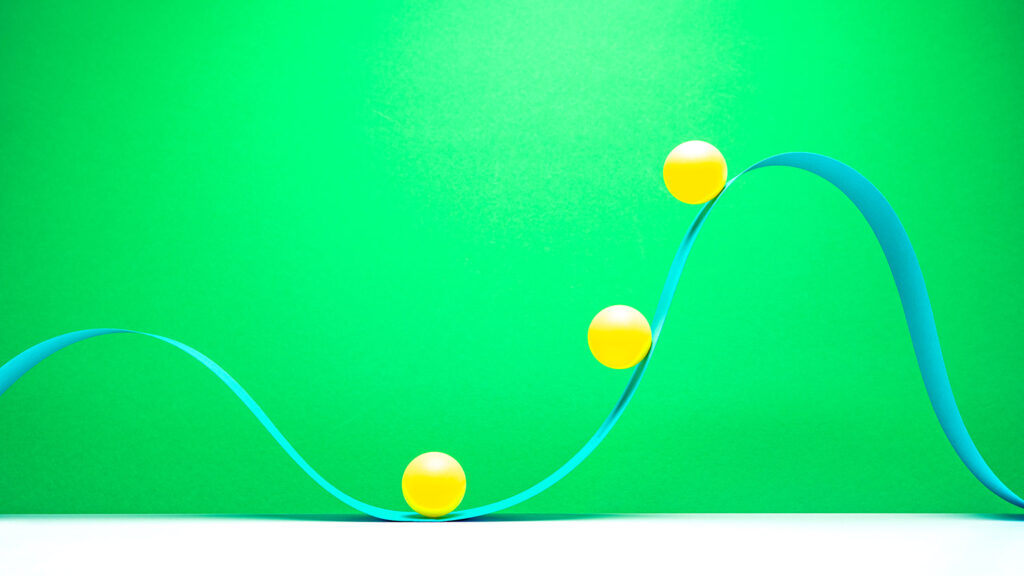 3 little yellow balls riding on blue paper in wave pattern on green background