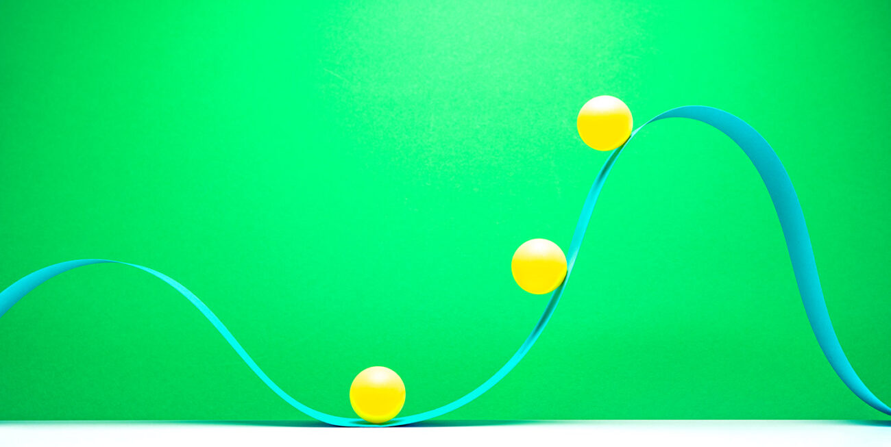 3 little yellow balls riding on blue paper in wave pattern on green background