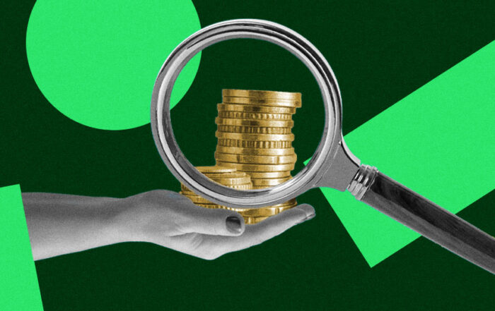 A hand holding coins while being magnified