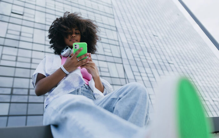 A woman looking at her green phone while sitting outside