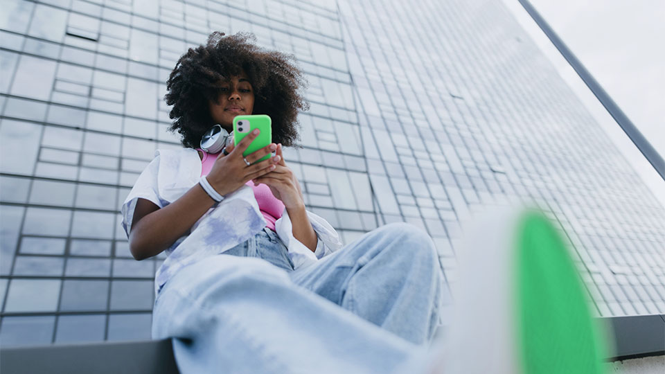 A woman looking at her green phone while sitting outside