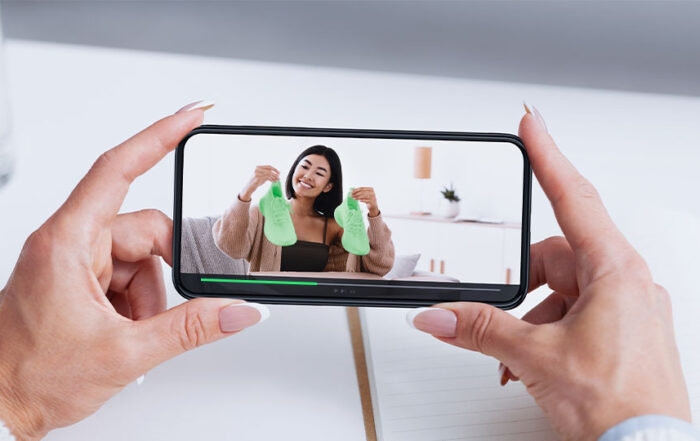 A pair of well-manicured hands watching an Amazon shoe review on their phone