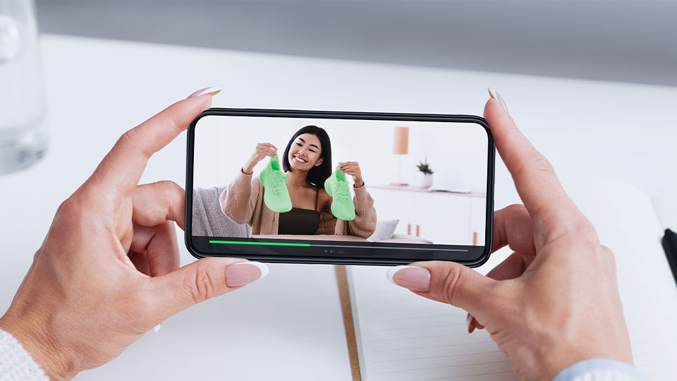 A pair of well-manicured hands watching an Amazon shoe review on their phone