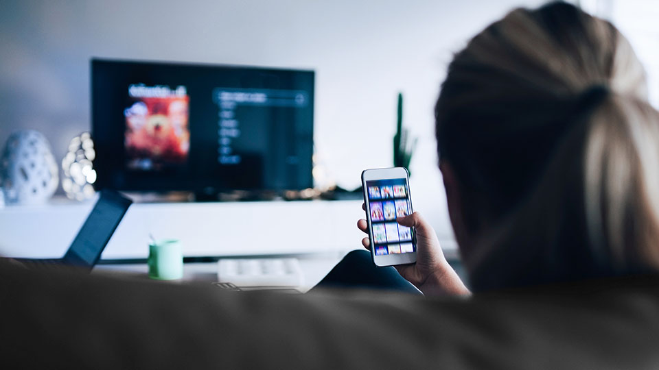 A woman consuming media through multiple screens