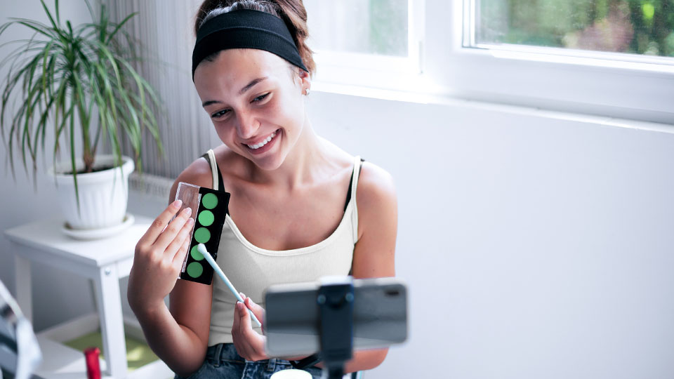 A woman showcasing their green makeup in front of a camera.