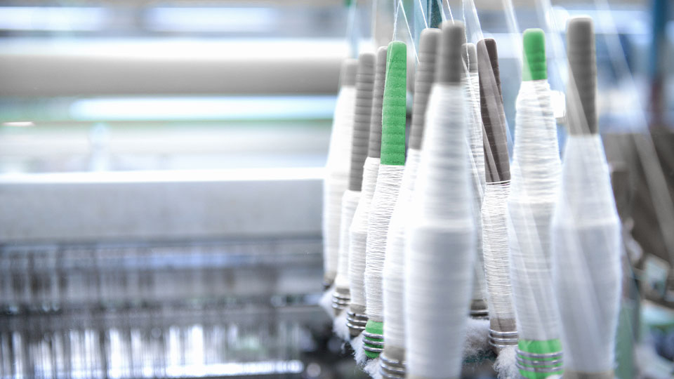 A close up of bobbins in industrial loom in textile mill
