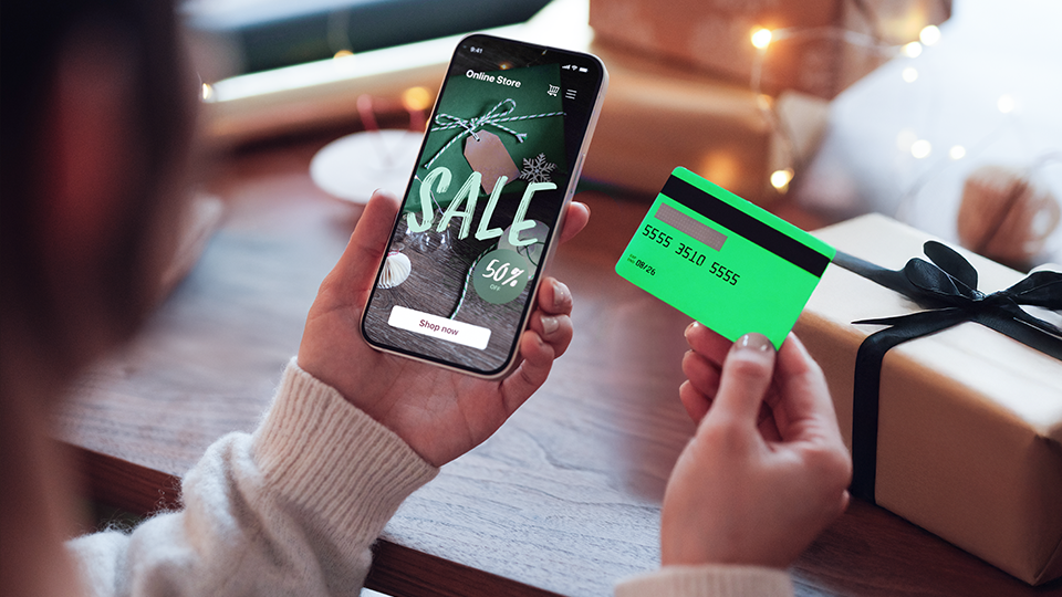 Someone making a holiday purchase on their cell phone with their credit card.