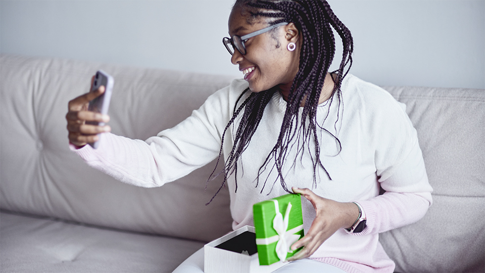 A woman taking a selfie after opening a present.