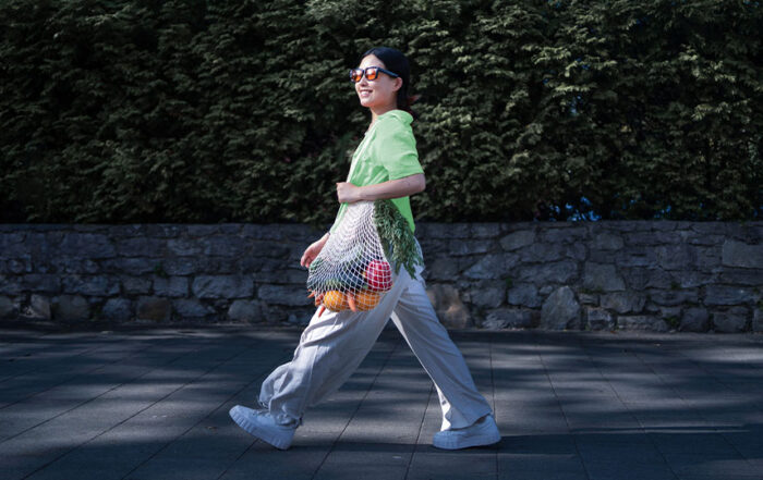 A woman enjoying their walk outside while carrying produce