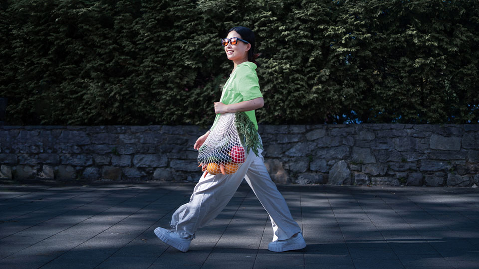 A woman enjoying their walk outside while carrying produce