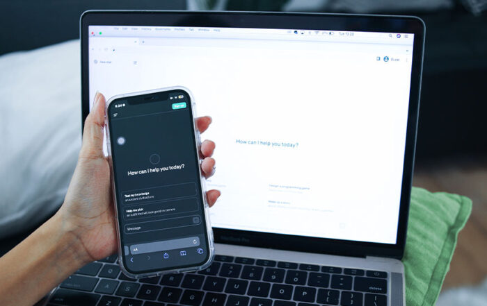 Someone holding their cell phone with the ChatGPT interface on the screen, while also having ChatGPT ready on their laptop screen.
