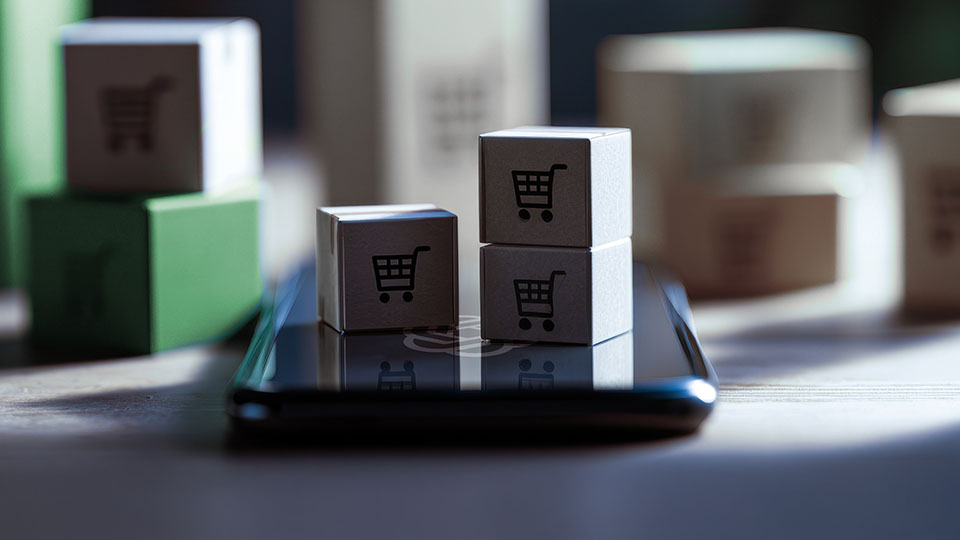 Three small boxes on top of a cell phone. The boxes have shopping cart icons on them.